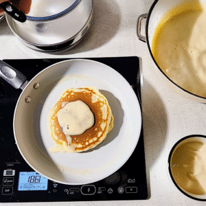 Cooking flapjacks in skillet with butter melting on top