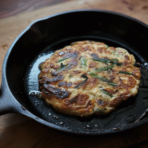 Green onion pancake cooking in cast iron skillet