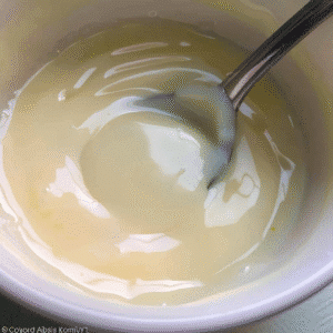 Bowl of glossy, homemade condensed milk with spoon